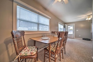A dining area with a wooden table and chairs, a window with blinds, and a ceiling fan. - Unplugged Bryson City Cabin Near Downtown (Bryson City)