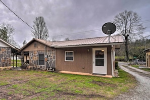 A single-story house with a stone exterior, a satellite dish, and a gravel driveway. - Unplugged Bryson City Cabin Near Downtown (Bryson City)