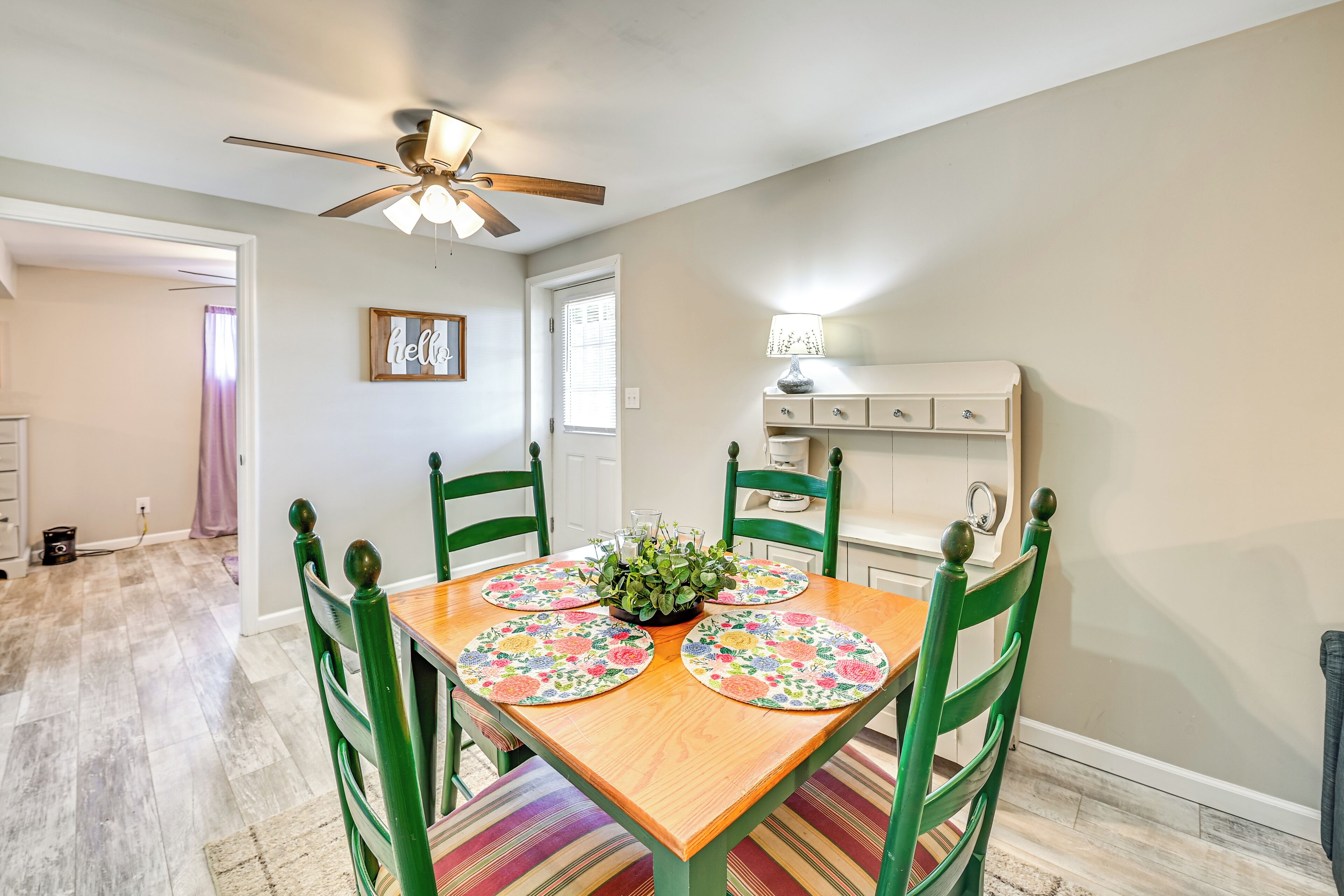 A dining area with a wooden table, green chairs, and a ceiling fan.