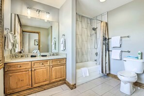 A bathroom with a wooden vanity, a large mirror, a shower, and a toilet. - Winter Park Condo w/ Mountain Views + Hot Tub (Winter Park)