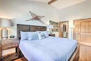 A bedroom with a large bed, wooden headboard, bedside tables, lamps, and a star decoration on the wall. - Winter Park Condo w/ Mountain Views + Hot Tub (Winter Park)