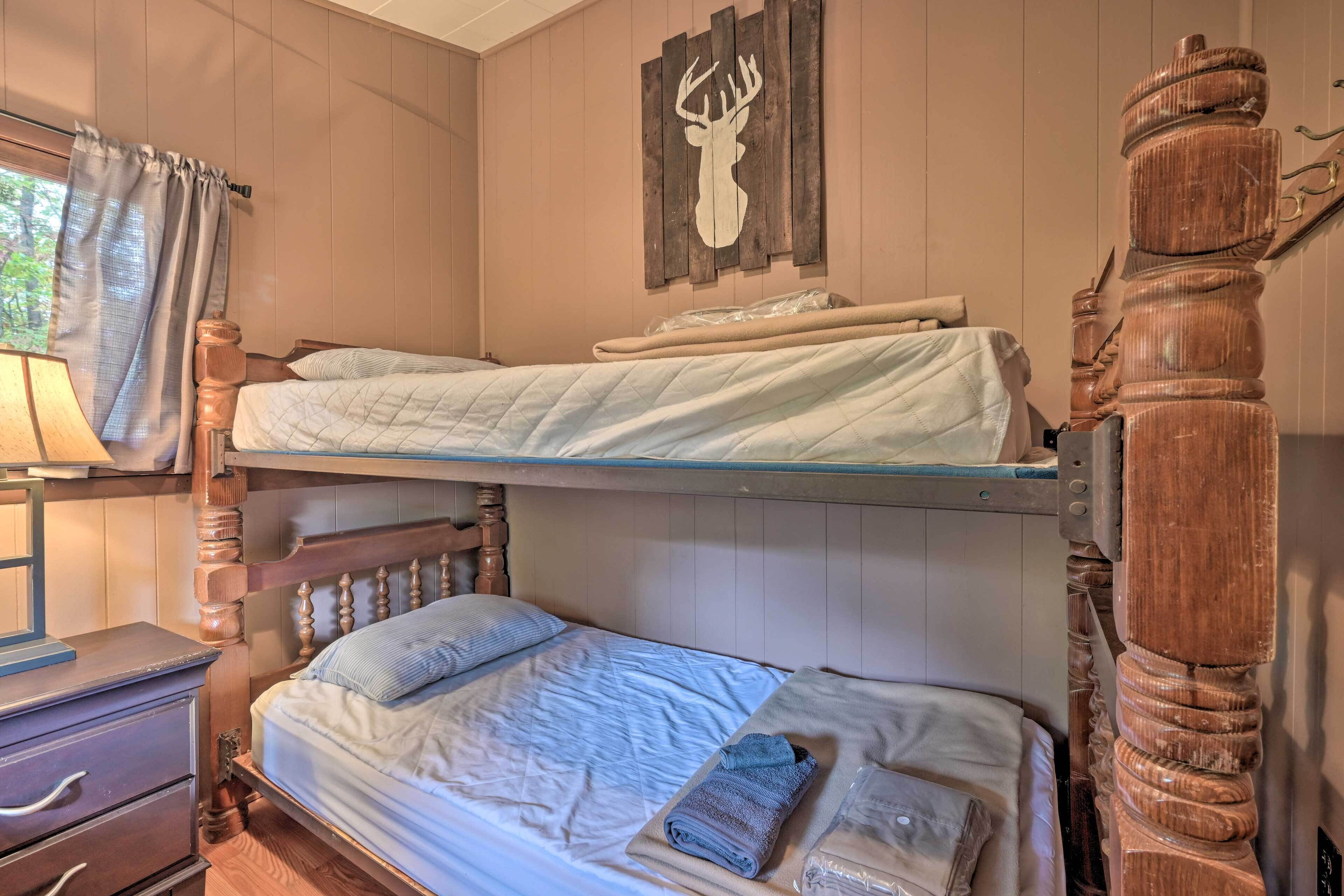 Una cama individual con cabecera de madera, una decoración de cabeza de venado en la pared y una ventana con cortinas.