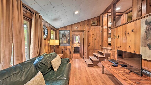 A wooden-paneled room with a leather sofa, a TV, and a staircase leading to another level. - 1 Mi to Raystown Lake: 'wyatt Earp Cabin' w/ Deck! (Huntingdon)
