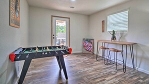 A room with a foosball table, a bar area with stools, and a door leading outside. - Updated Knoxville Home w/ Media Room + Patio! (Knoxville)