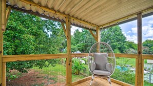 A wooden deck with a hanging chair, a view of a garden, and a pool. - Updated Knoxville Home w/ Media Room + Patio! (Knoxville)
