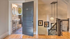A modern interior with a dark wooden door, a bathroom with a white sink, and a staircase with a metal railing.