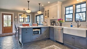 A modern kitchen with grey cabinetry, a central island, a built-in microwave, and a dishwasher.