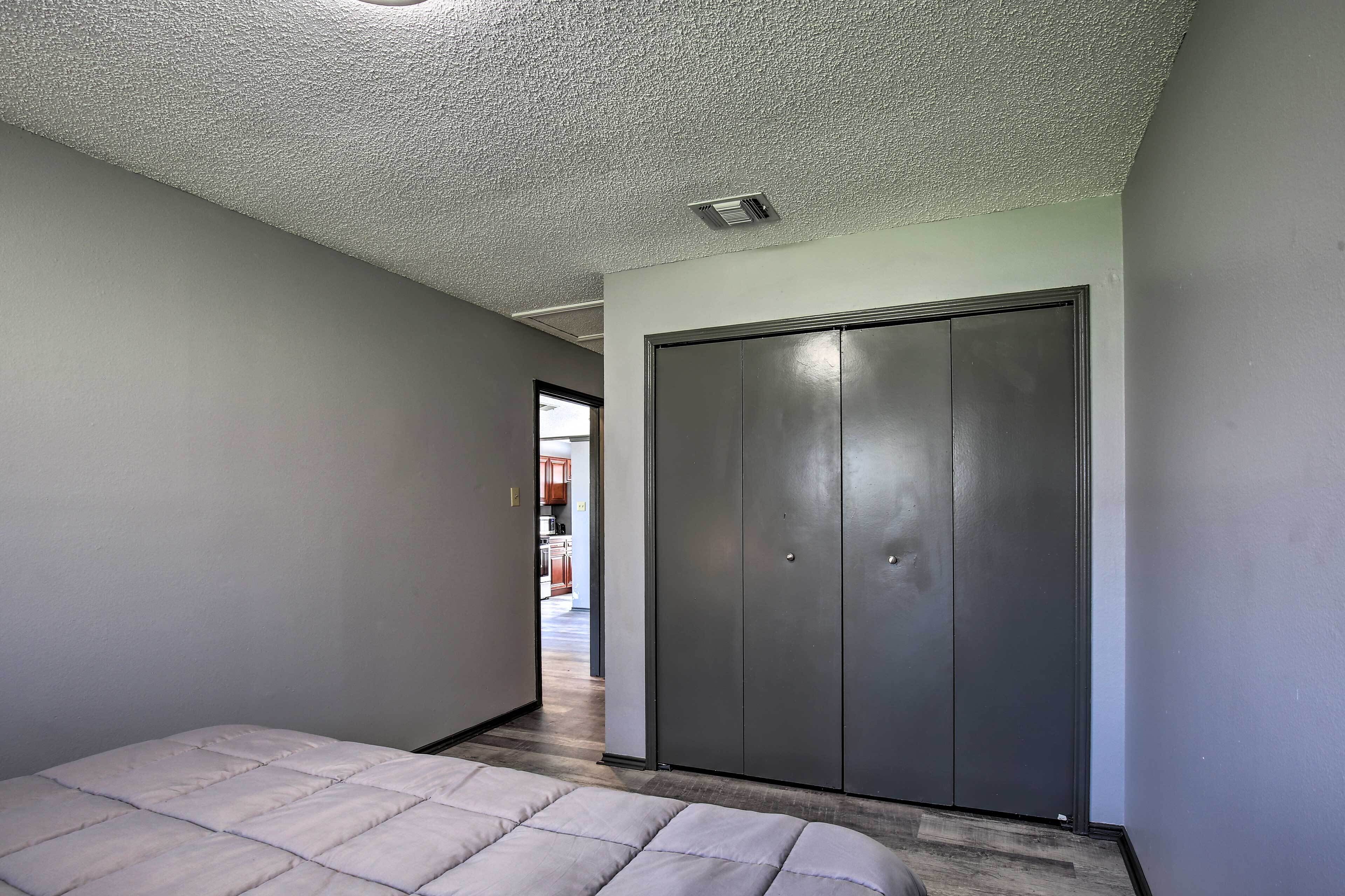 A bedroom with a bed, a wardrobe, and a ceiling vent.