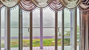 A view from a room with large glass doors leading to a deck overlooking a body of water. - Waterfront House w/ Glacial Views - Near Downtown! (Juneau)