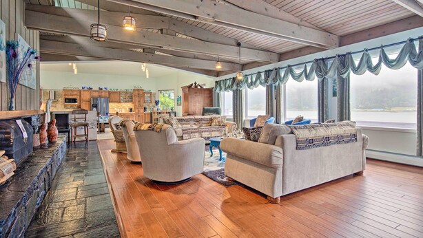 A spacious living room with a fireplace, comfortable seating, and large windows overlooking a scenic view. - Waterfront House w/ Glacial Views - Near Downtown! (Juneau)