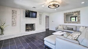 A modern living room with a fireplace, a large mirror, and a sectional sofa. - Waterfront Lake Home w/ Deck - New Renovations! (Willis)