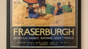 A framed poster advertising Fraserburgh with a beach scene, including people, a boat, and buildings. - Stag & Thistle Hotel and Restaurant (Fraserburgh)
