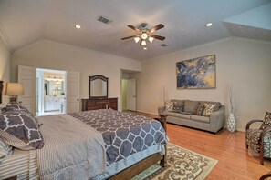 A bedroom with a large bed, a ceiling fan, a sofa, and a painting on the wall. - 2,500 Sq Ft Townhome - Walk to Central River Oaks! (Houston)
