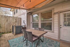 A covered patio with a wooden table and chairs, a patterned rug, and a wooden fence. - 2,500 Sq Ft Townhome - Walk to Central River Oaks! (Houston)