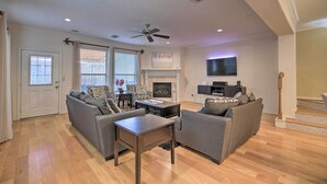 A spacious living room with a fireplace, a ceiling fan, and a flat-screen TV mounted on the wall. - 2,500 Sq Ft Townhome - Walk to Central River Oaks! (Houston)