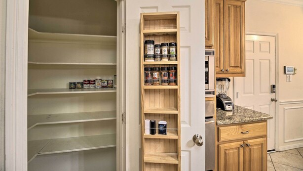 A kitchen with wooden cabinets, a built-in spice rack, and a countertop with a blender. - 2,500 Sq Ft Townhome - Walk to Central River Oaks! (Houston)