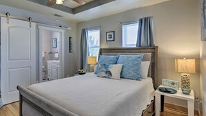 Une chambre à coucher avec un lit, des tables de chevet, un ventilateur de plafond et une vue sur la salle de bain.
