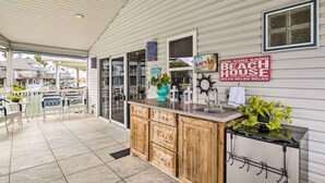 Une maison de plage dotée d’une cuisine, d’un coin repas avec des sièges à l’extérieur et d’une pancarte publicitaire pour la propriété.