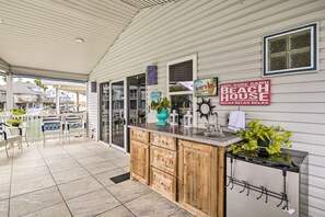 Una casa de playa con cocina, comedor al aire libre y un cartel anunciando la propiedad.