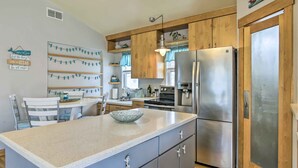 Une cuisine avec des meubles en bois, un réfrigérateur en acier inoxydable et un plan de travail en granit.