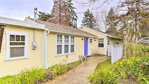 A yellow single-story house with a blue front door, a small porch, and a concrete pathway leading to the entrance.