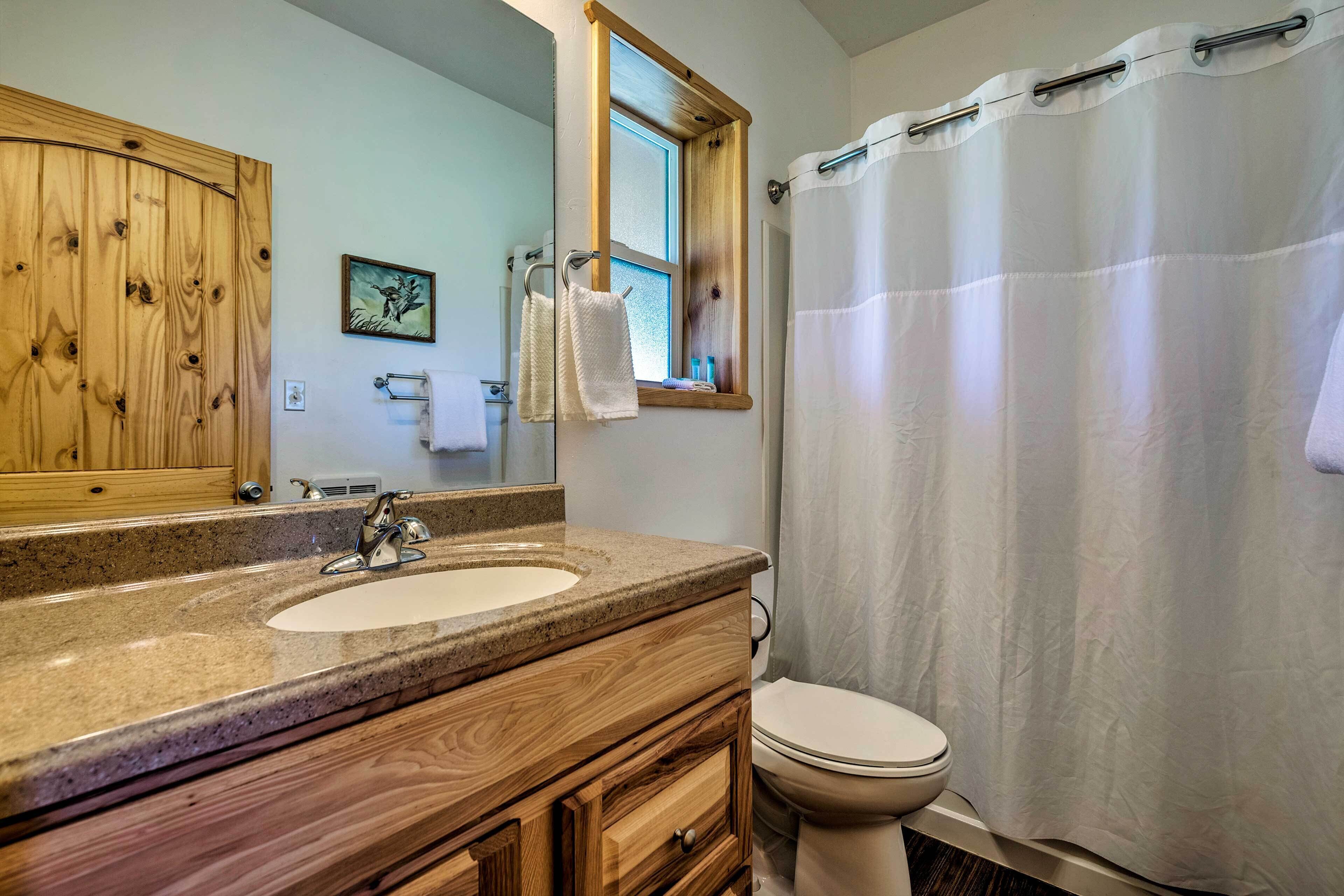 A bathroom with a wooden vanity, a sink, a toilet, and a shower curtain.