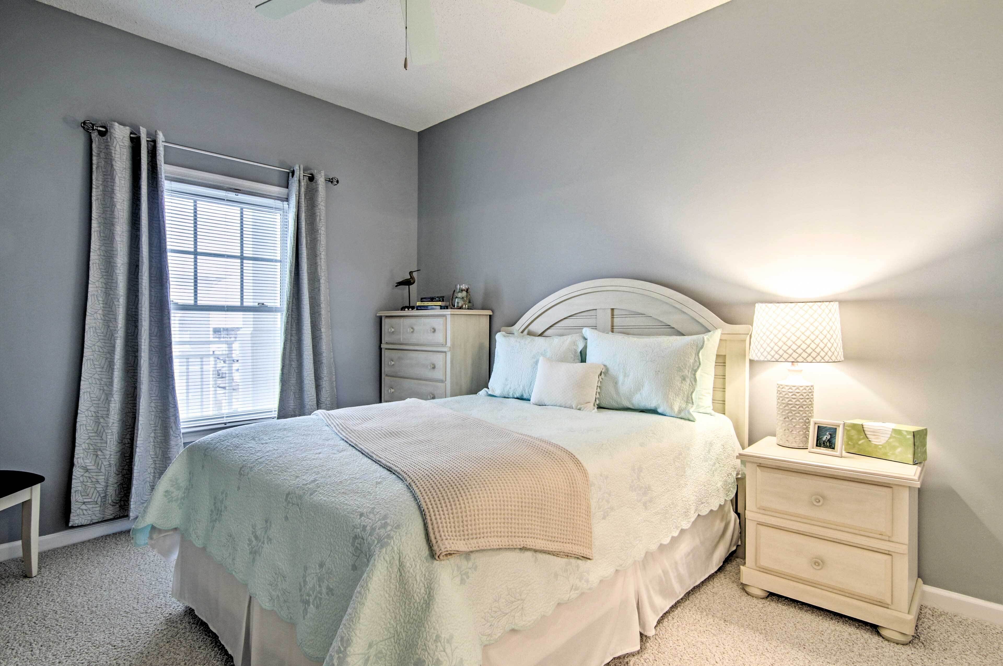 A bedroom with a bed, nightstand, dresser, and a window with curtains.