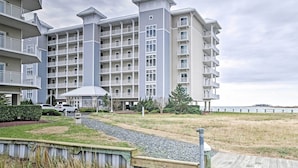 Un hotel de varios pisos con balcones, una galería techada y vista a la playa.