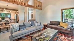 A spacious living area with a high wooden ceiling, a grey sofa, a brown sofa, and a glass coffee table. - Hike, Fish, & Relax: Family Arnold Cabin (Arnold)