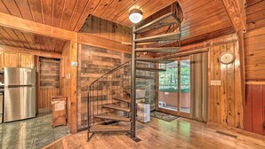 A wooden interior with a spiral staircase, a stainless steel refrigerator, and a large window. - A-frame Gatlinburg Cabin w/ Deck & Private Hot Tub (Gatlinburg)