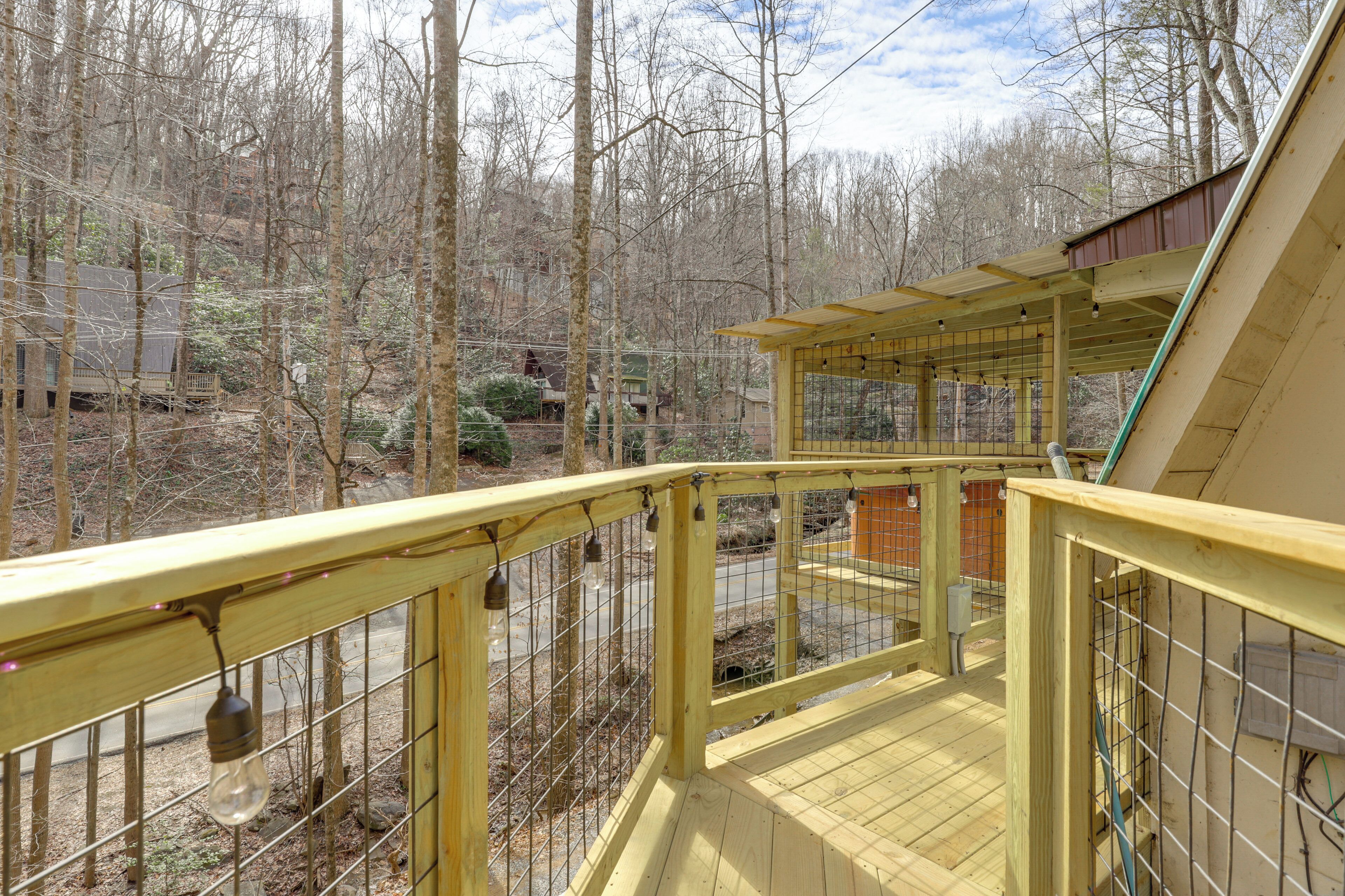 A wooden deck with a metal railing overlooking a forested area.