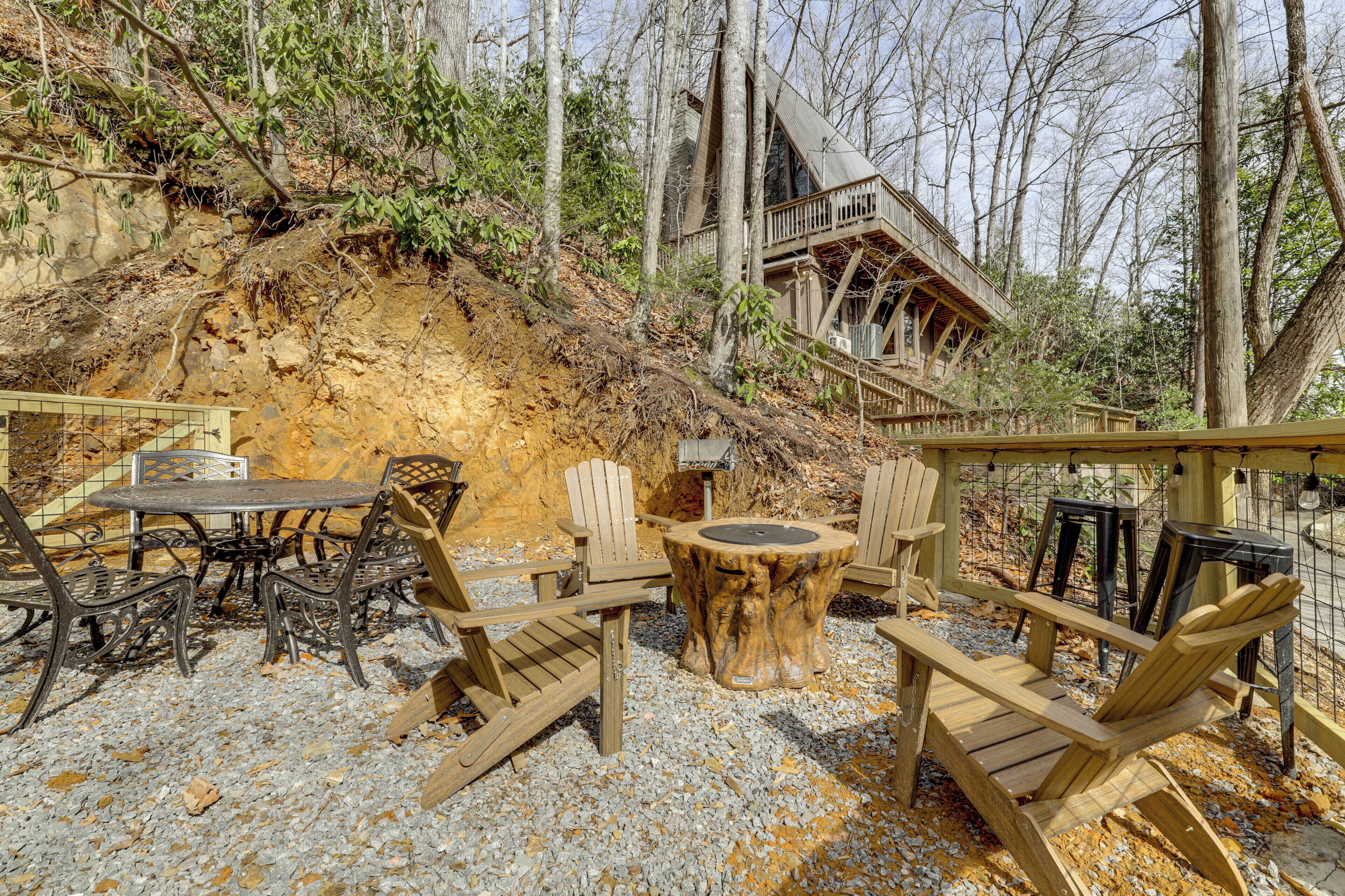A wooden deck with a table and chairs, surrounded by trees and a wooden structure with a balcony.