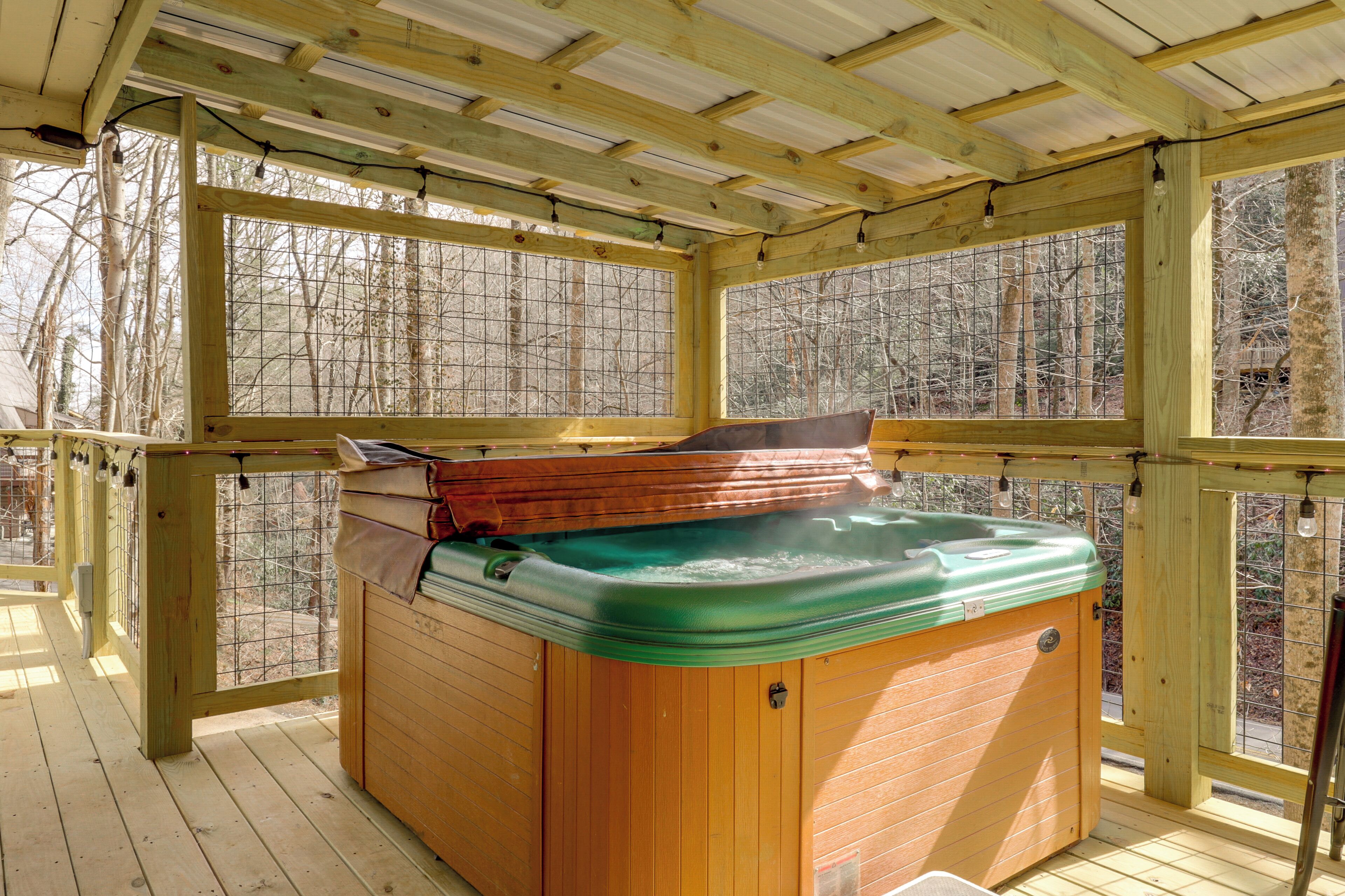 A wooden deck with a hot tub, wooden walls, and large windows.
