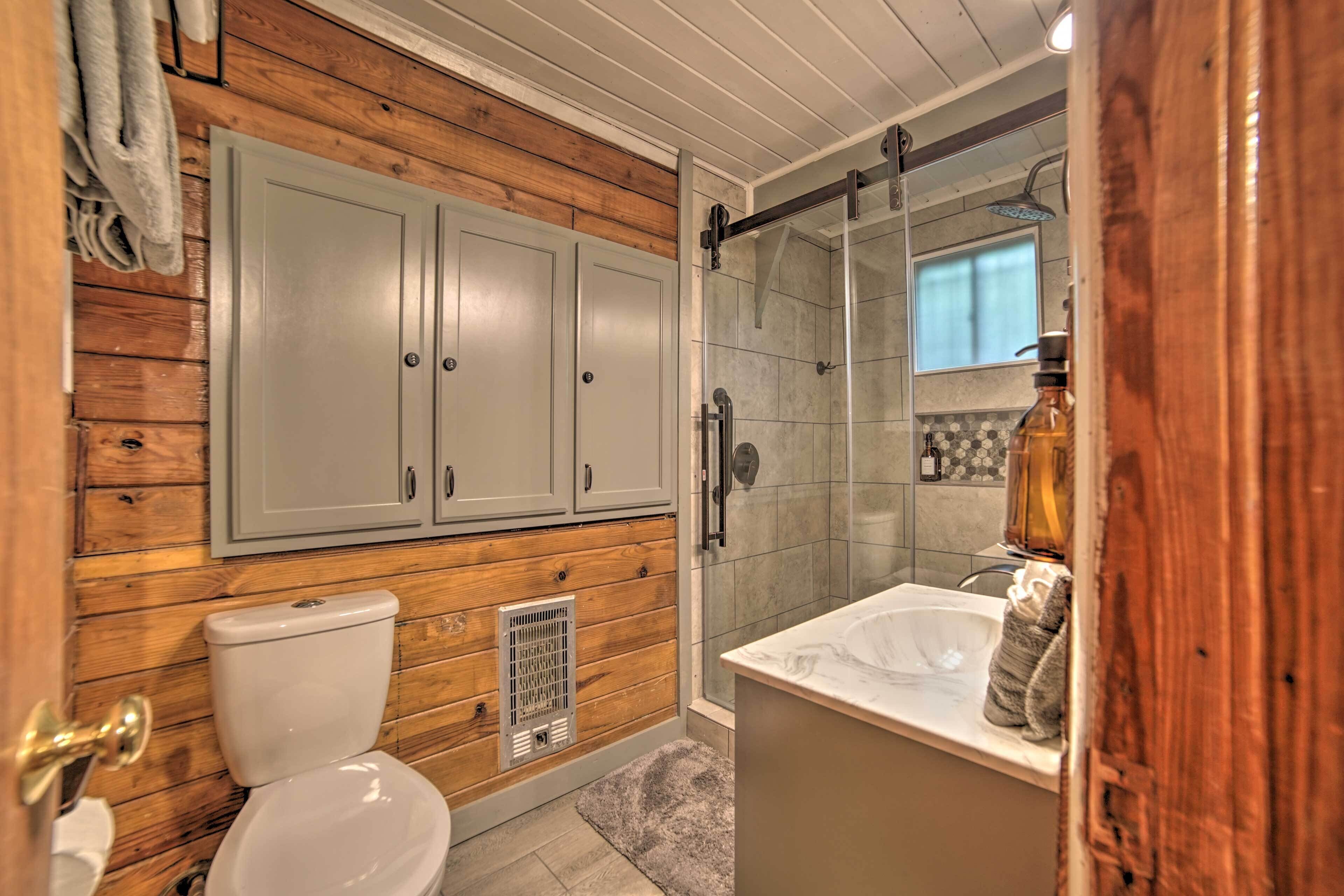 Une salle de bain avec des lambris en bois, des toilettes, une douche avec des portes en verre et un lavabo doté d'un plan de travail en marbre.