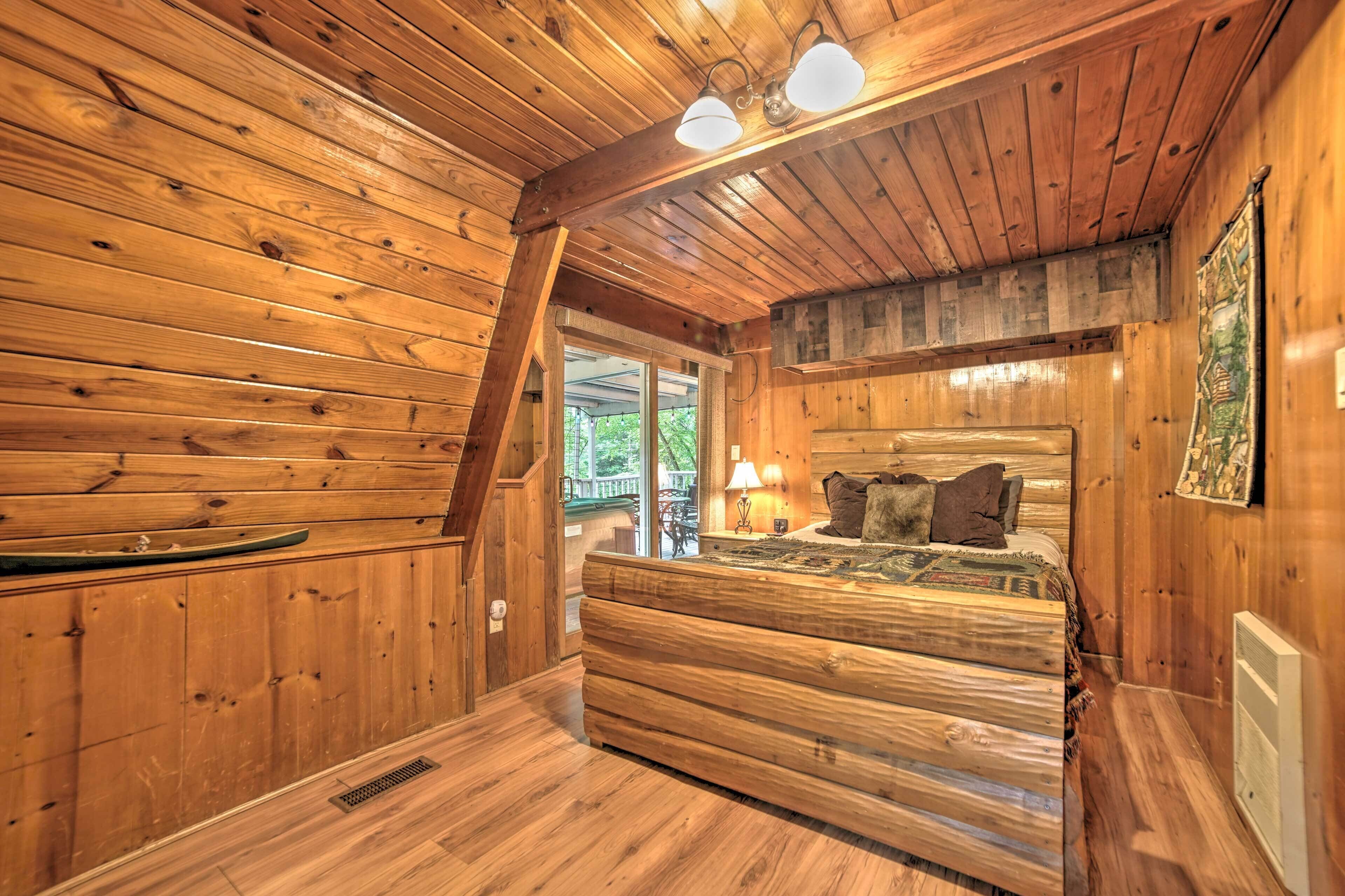 Un dormitorio de cabaña de madera con una cama, una mesita de noche y una ventana.