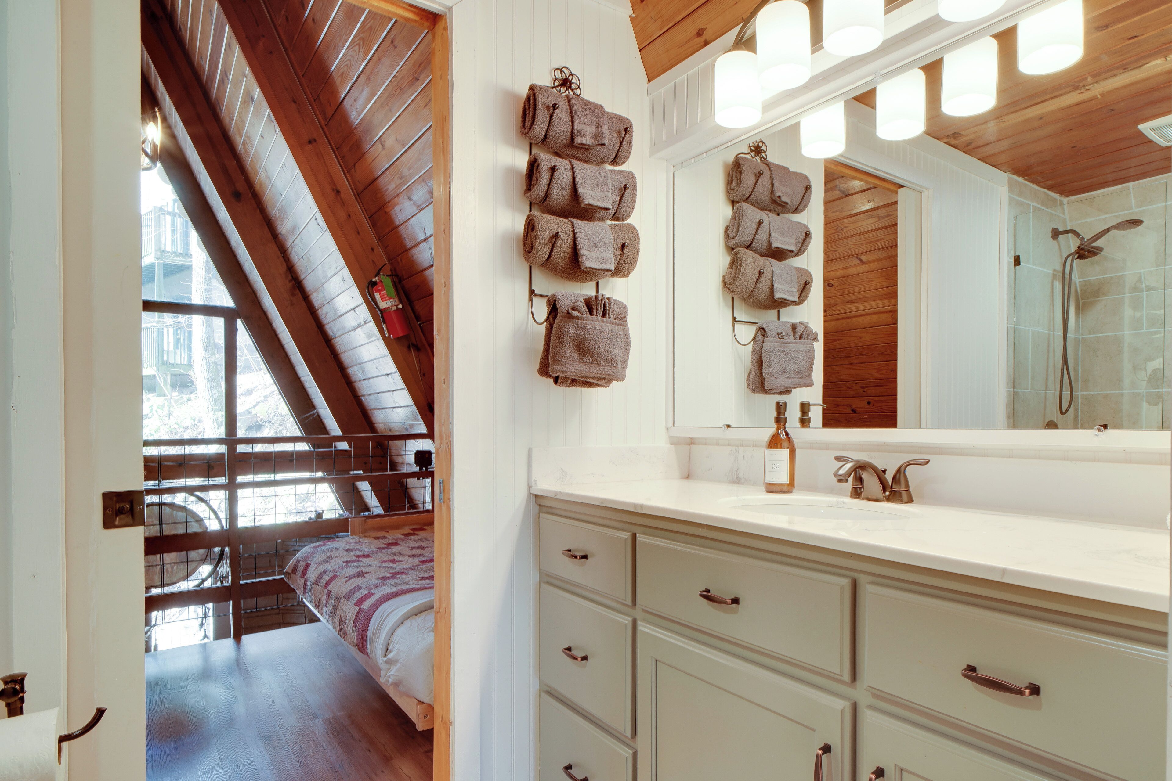 A bedroom with a sloped ceiling, a large window, and a bed with a patterned bedspread.
