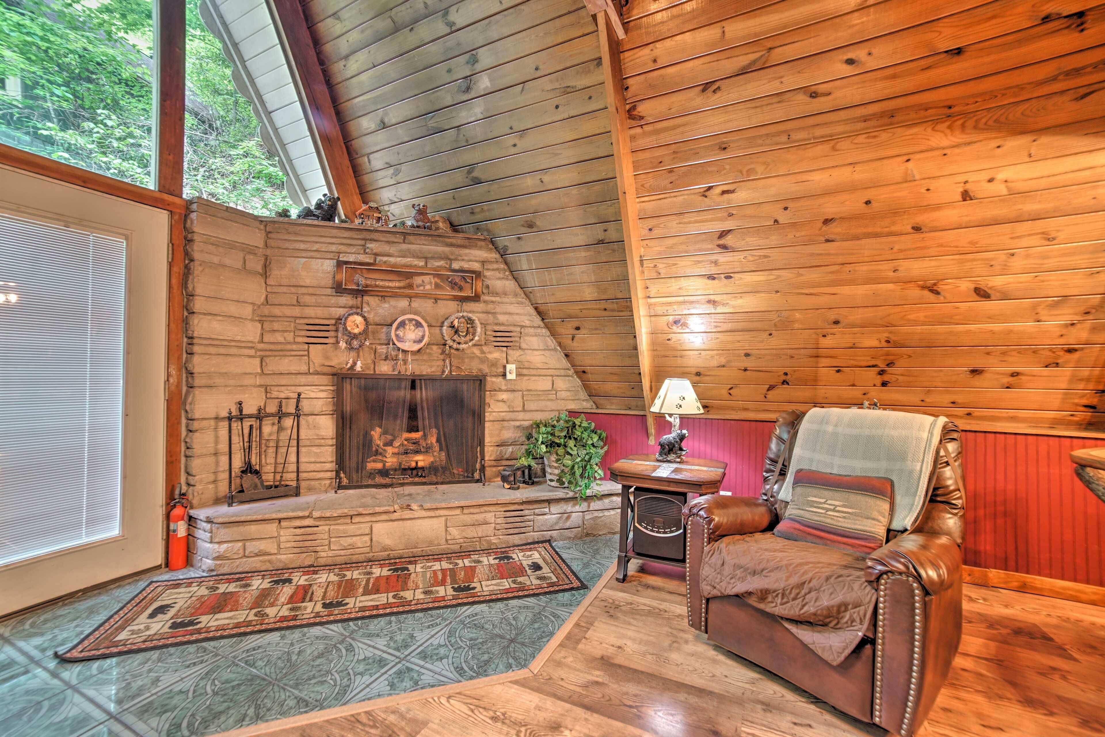 A cozy cabin interior with a stone fireplace, leather armchair, and wooden walls.