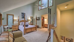 Een ruime slaapkamer met een groot bed, een plafondventilator en uitzicht op de omgeving.