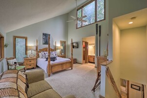 Un dormitorio amplio con una cama grande, ventilador de techo y vistas al exterior a través de una ventana.