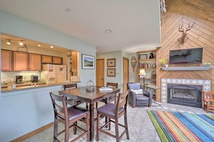 Una cocina moderna con armarios de madera, una mesa de comedor con sillas, una chimenea y un televisor de pantalla plana montado encima.