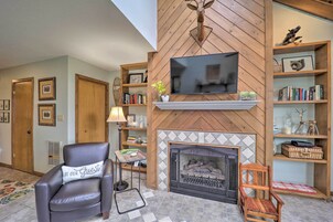 Una sala de estar con chimenea, televisor y estanterías de madera con libros y adornos.