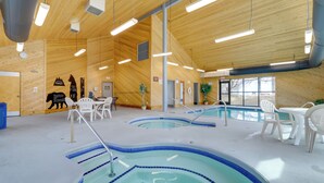 En indendørs swimmingpool med flere baner, trævægge og hvide plastikstole.