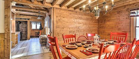 Ein Esszimmer mit Holztisch, gedeckt für sechs Personen, umgeben von roten Stühlen.