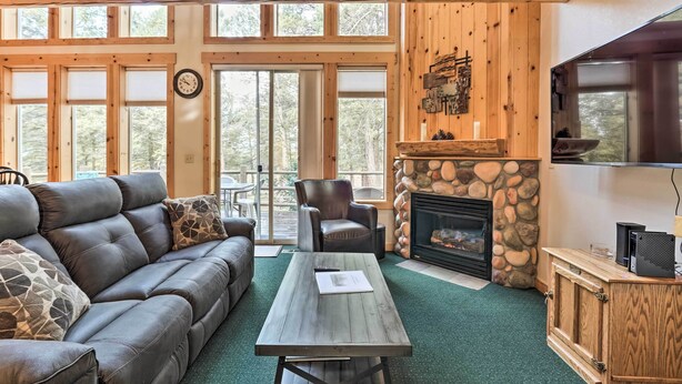 A cozy living room with a leather sofa, a stone fireplace, and a television.