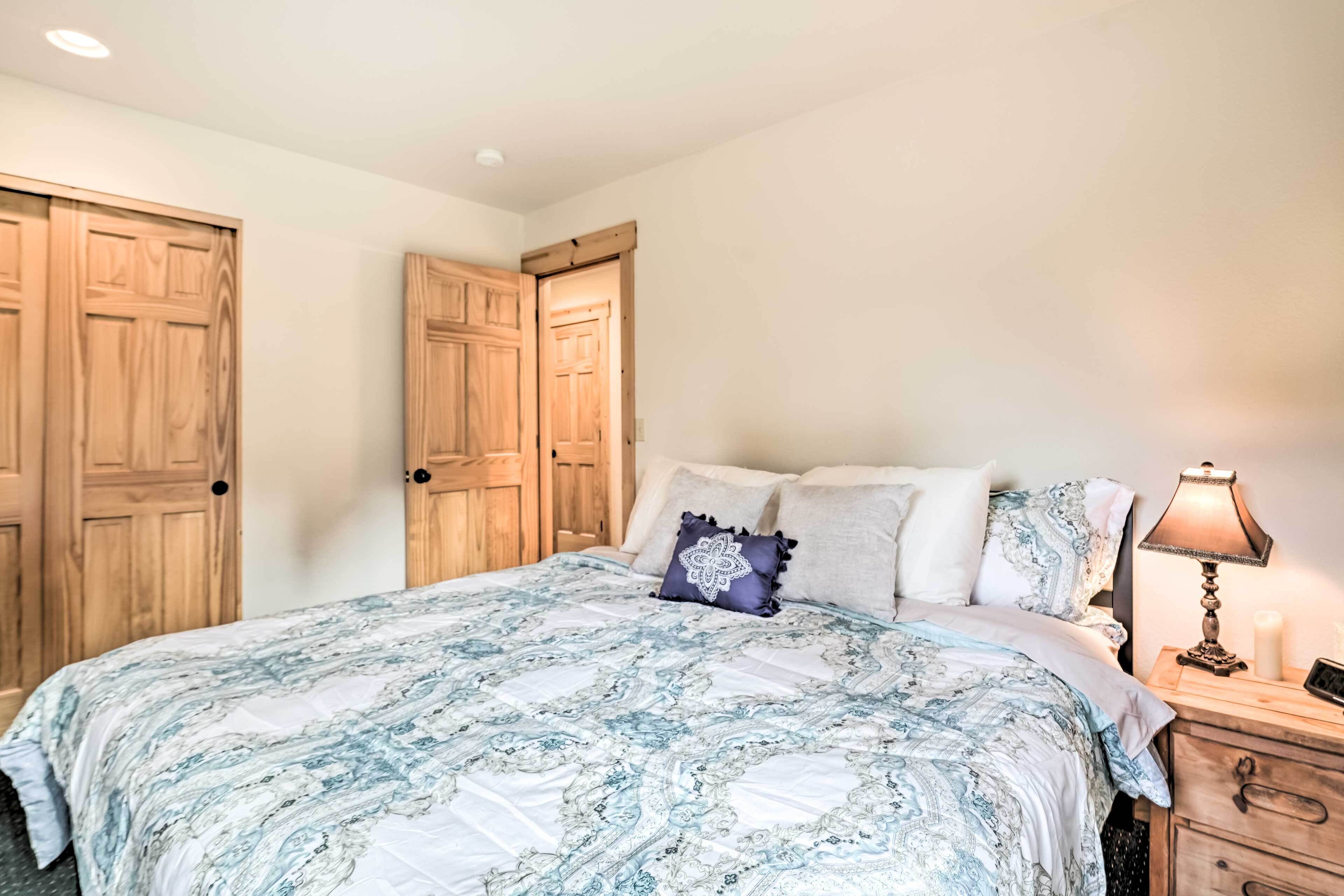 A bedroom with a large bed, wooden wardrobe, and bedside table with a lamp.