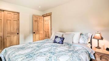 A bedroom with a large bed, wooden wardrobe, and bedside table with a lamp.