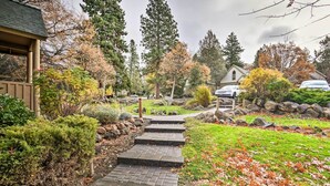 A pathway leading to a house with a stone staircase, surrounded by autumn foliage and various shrubs.