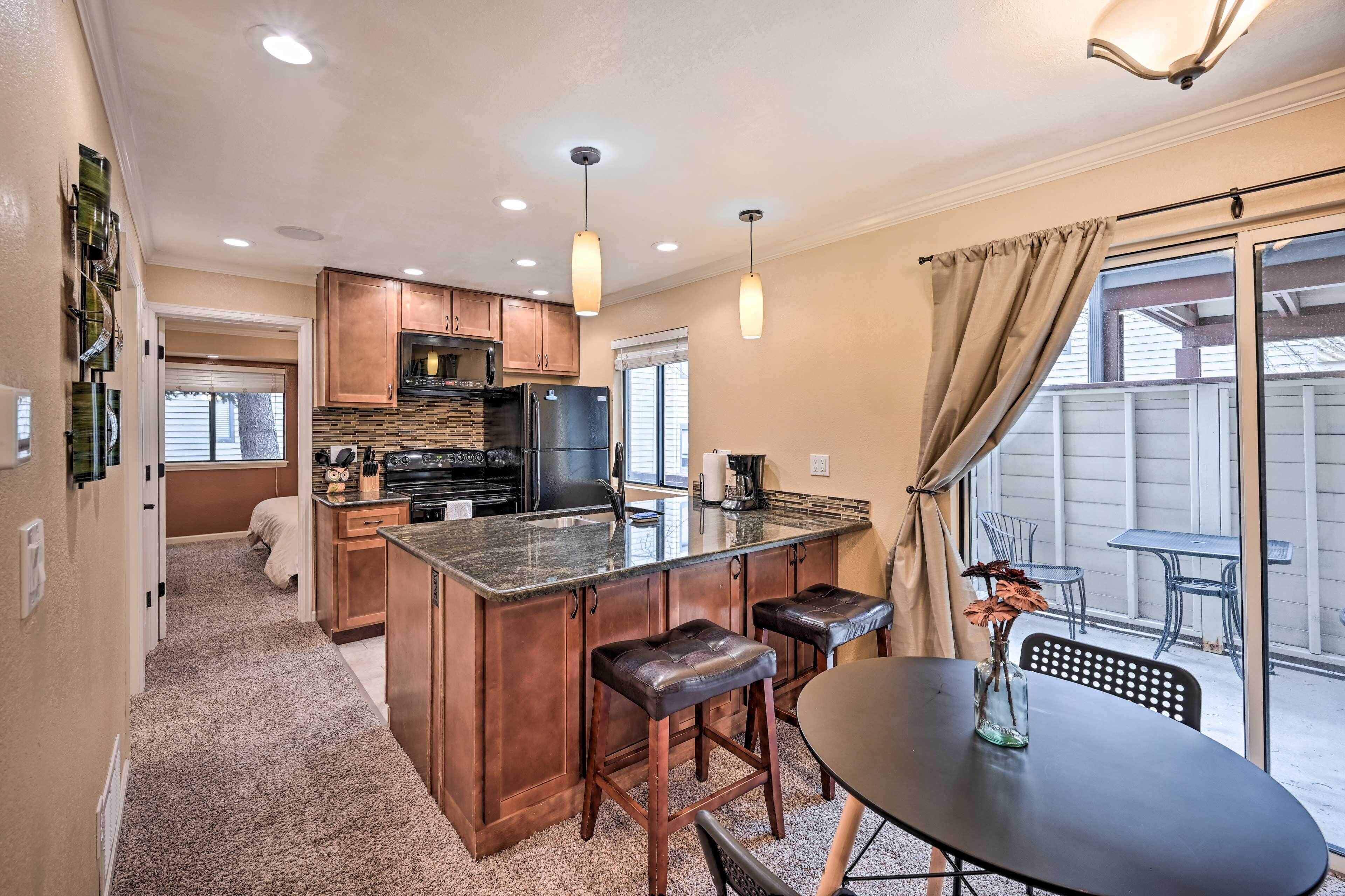 A modern kitchen with a central island, bar stools, and a dining table with a vase.