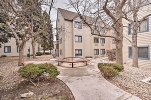 A courtyard with a central bench, surrounded by trees and a building with multiple windows.