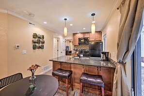 A kitchen with a central island, pendant lights, and a dining area with a table and bar stools.